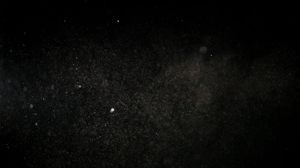 Close-up of dust particles floating in space against a black background.