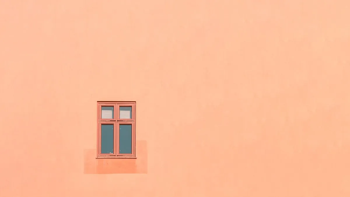 An orange wall with a single window in Oslo, showcasing minimalist architecture.