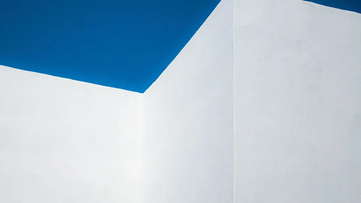 A striking minimalist image of a geometric white wall set against a clear blue sky in Rabat, Morocco.