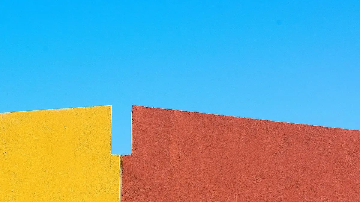 Bright yellow and red walls contrasting with a vivid blue sky in a minimalist style.