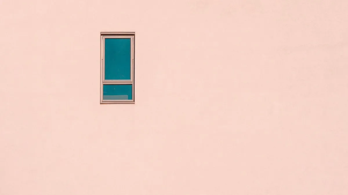 A minimalist pastel pink wall featuring a single rectangular window, offering ample negative space.