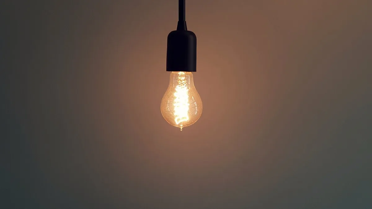 Simple illuminated light bulb hanging in a dark room, creating a warm atmosphere.