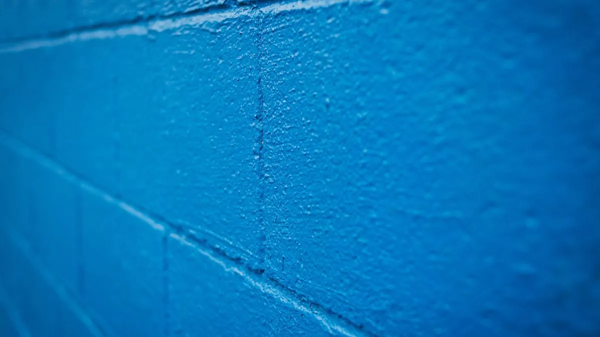 Uneven surface of rough brick wall painted in bright blue color in selective focus
