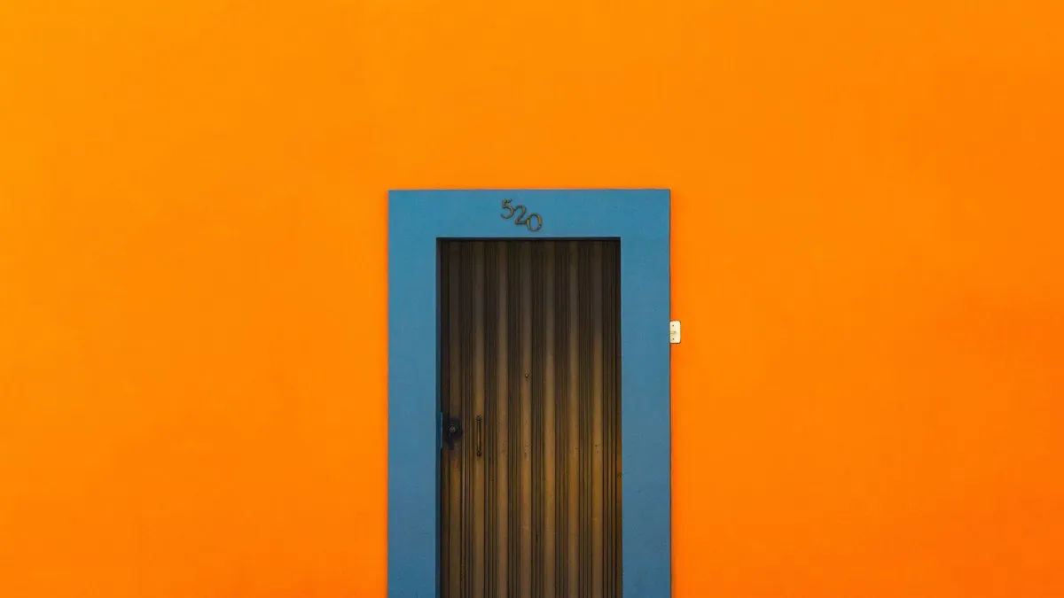 Exterior of bright orange wall of building with door with metal casing and drawing in daylight in city street outside