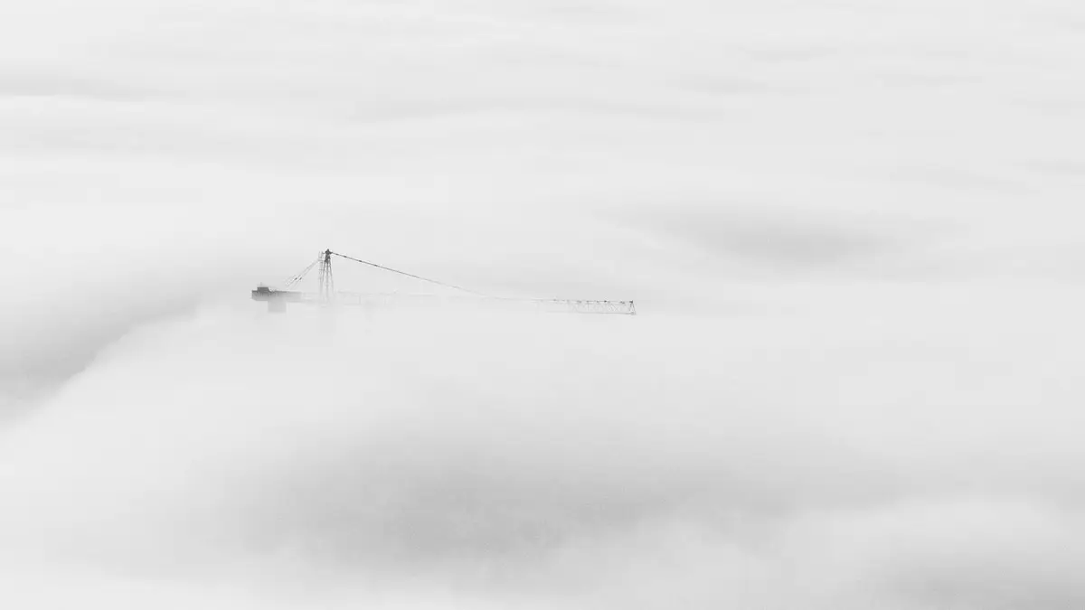 Ethereal view of a crane breaking through dense fog in Dubai, showcasing urban construction.