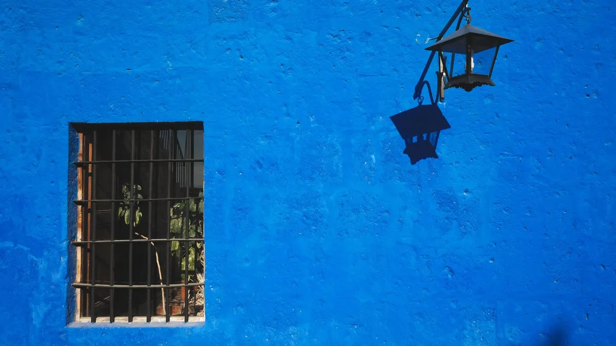 Bright blue wall with window and lantern shadow in Arequipa, Peru.