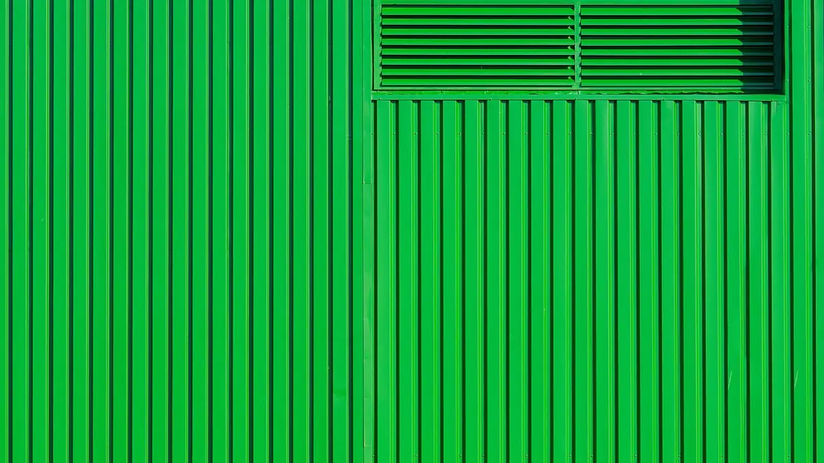 Close-up of a modern green metal wall with vertical patterns and ventilation detail.