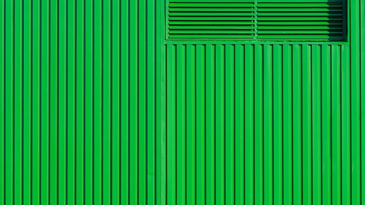 Close-up of a modern green metal wall with vertical patterns and ventilation detail.
