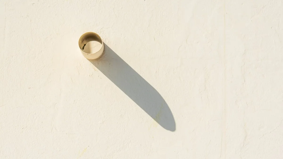 A long shadow cast by a pipe on a sunlit white wall, perfect for abstract and minimalist themes.