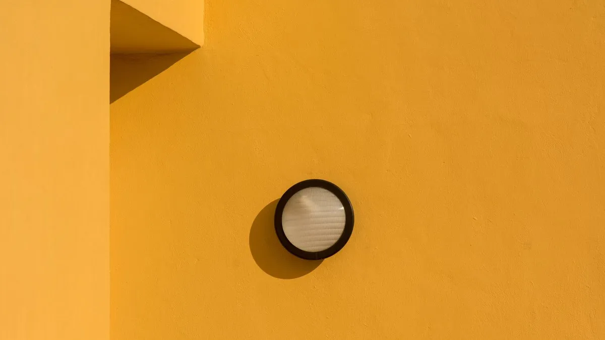 A simple and elegant light fixture casting shadows on a yellow wall, capturing minimalism.