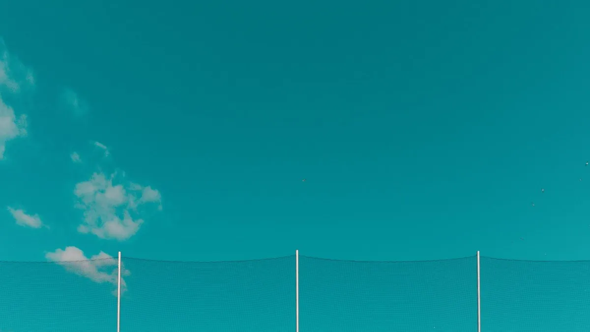 Minimalist outdoor scene with a teal sky, gentle clouds, and netting. Ideal for backgrounds.