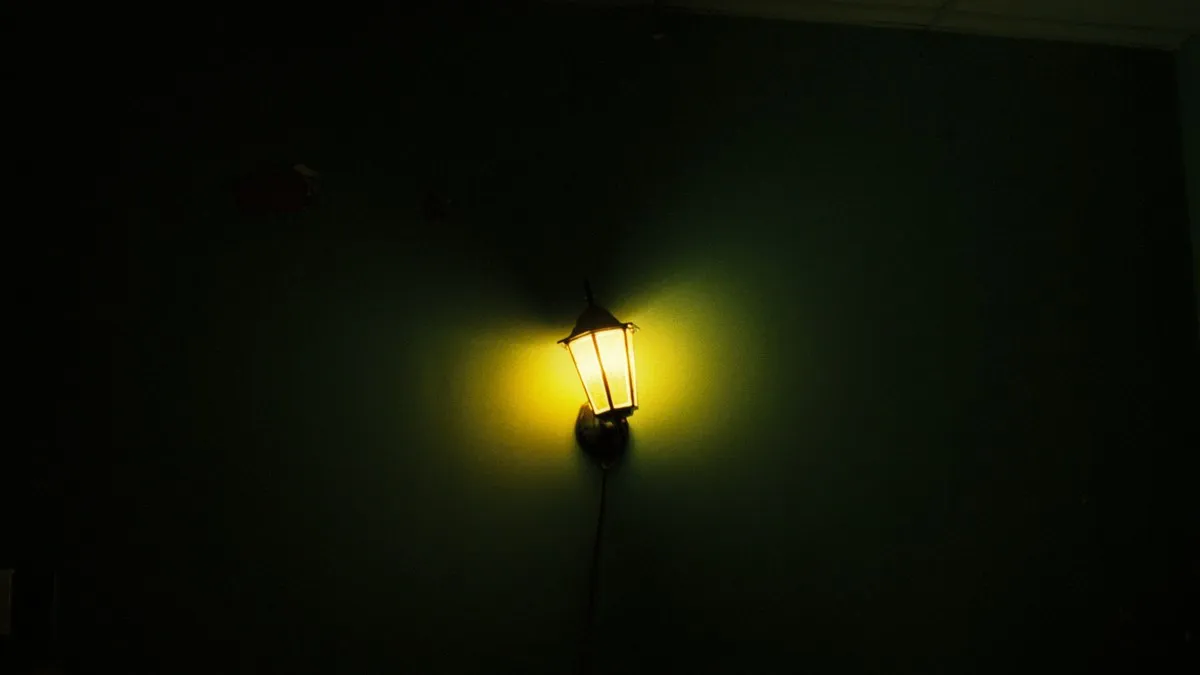 A single wall lantern emitting a warm glow against a dark green wall, creating a cozy atmosphere.