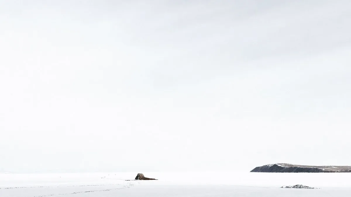 Snow-covered landscape capturing the peaceful winter beauty of Kharantsy, Russia with rocks and distant hills.