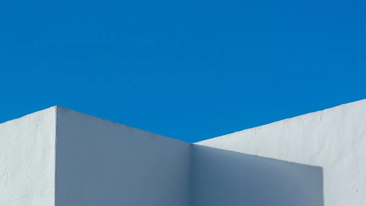 Minimalist design featuring a white wall against a vivid blue sky, showcasing modern architectural aesthetics.