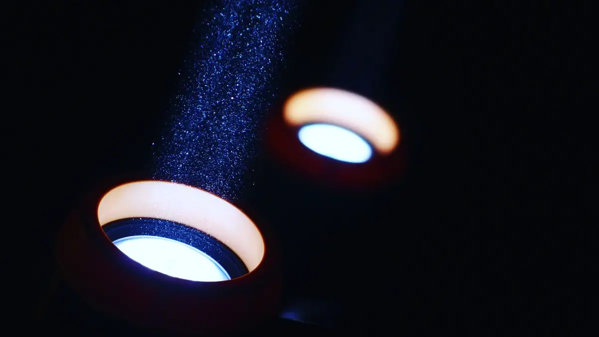 A striking visual of light beams illuminating particles in a dark setting, creating an abstract effect.