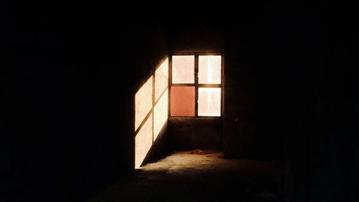 Sunlight casting dramatic shadows through a window in a dark room.